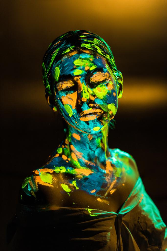 Πορτρέτο γυναίκας ζωγραφισμένα με φωτεινές νέον χρώματα σε σκούρο φόντο - Φωτογραφία, εικόνα