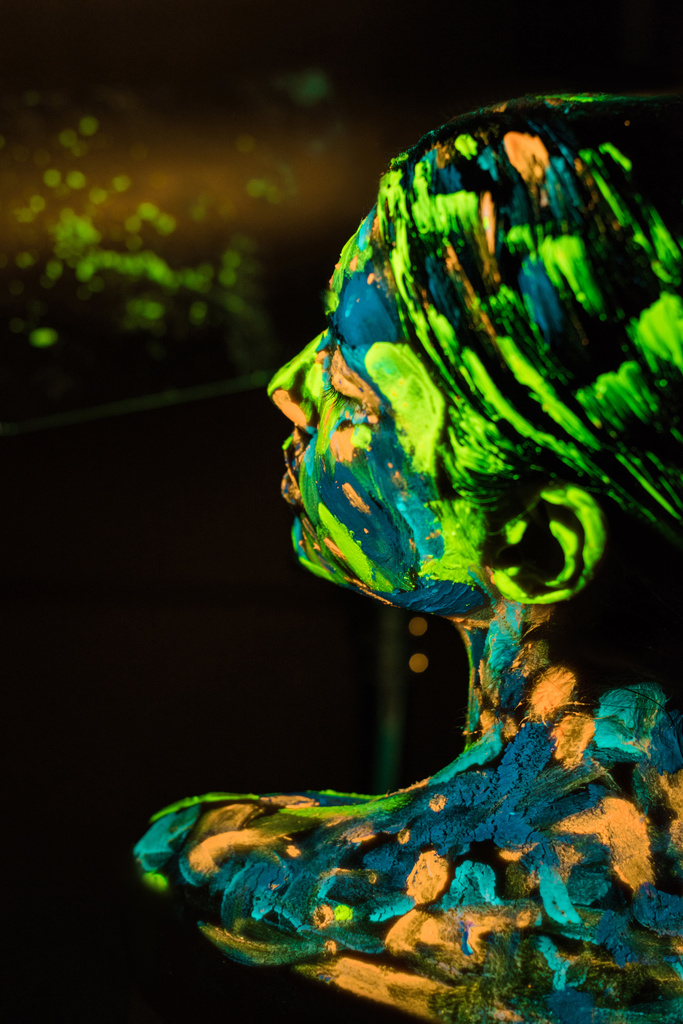 Achteraanzicht van een model met kleurrijke neon verf op lichaam op zwarte achtergrond - Foto, afbeelding
