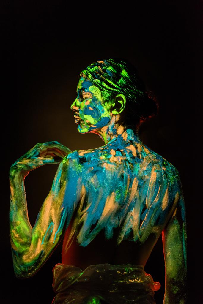 back view of model with colorful neon paints on body on black background - Photo, Image