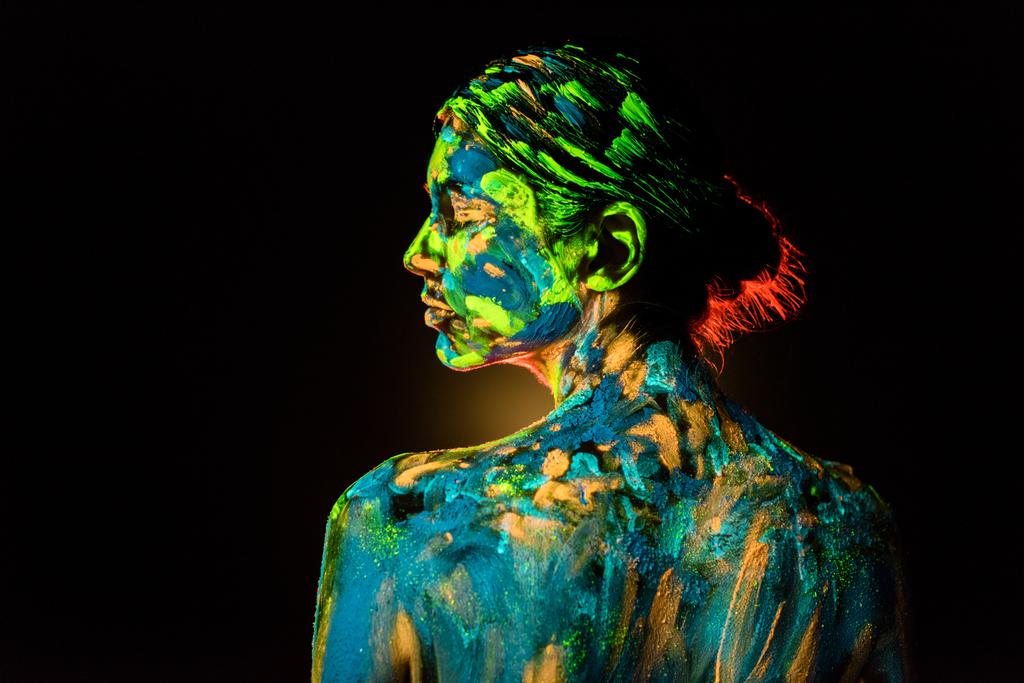back view of model with colorful neon paints on body on black background - Photo, Image