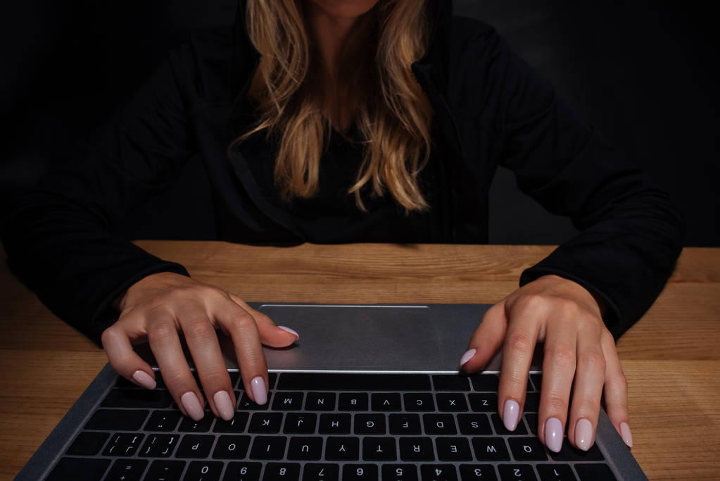 vista parcial del hacker femenino usando portátil digital en la mesa de madera
 - Foto, Imagen