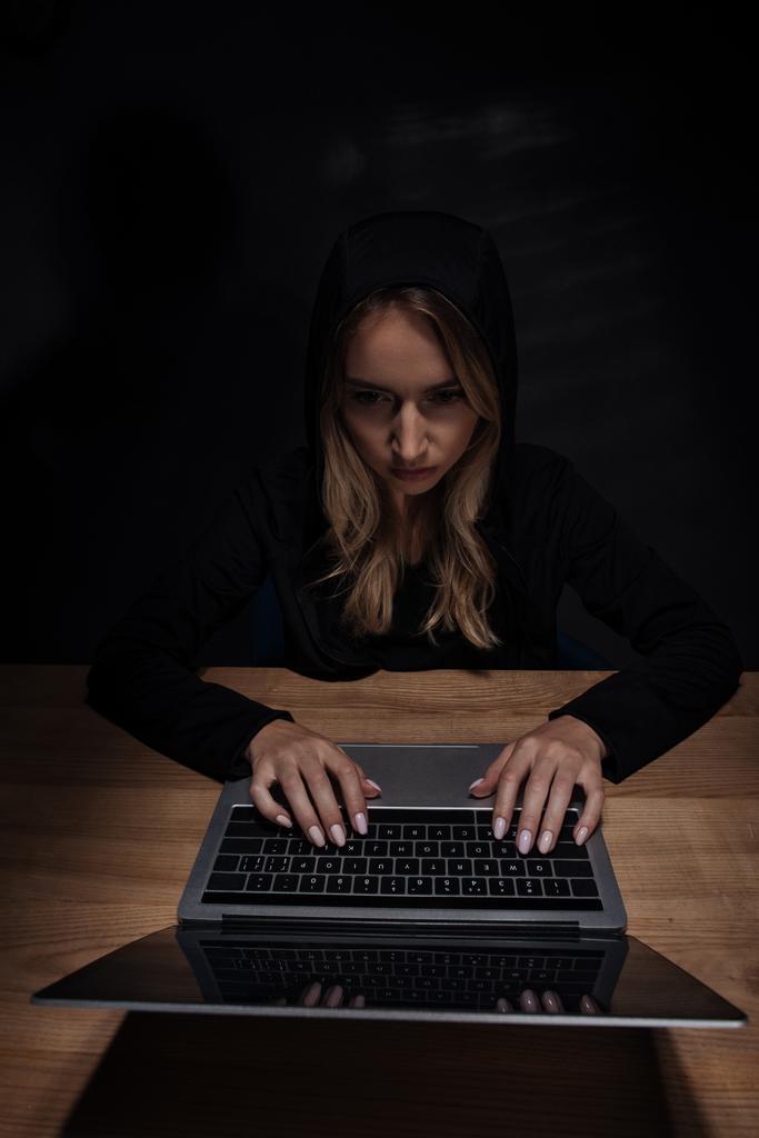 mulher de capuz preto usando laptop, conceito de segurança cibernética
 - Foto, Imagem