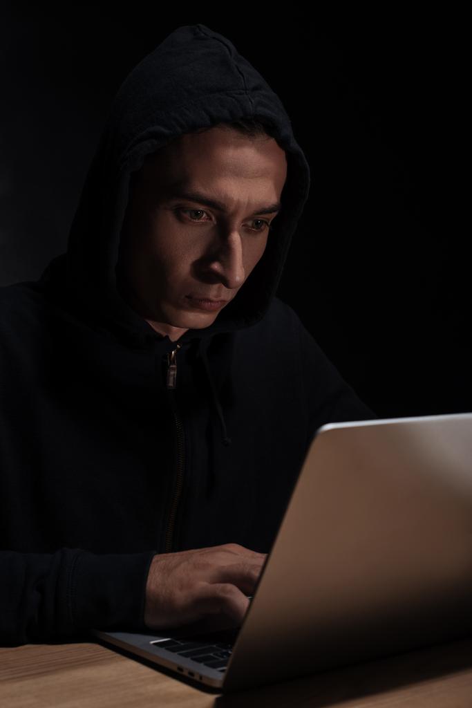 hacker in black hoodie using laptop, cuber security concept - Photo, Image
