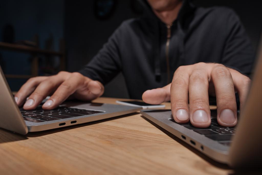 частичный просмотр хакера с помощью ноутбуков на рабочем столе со смартфоном, концепция кибербезопасности
 - Фото, изображение