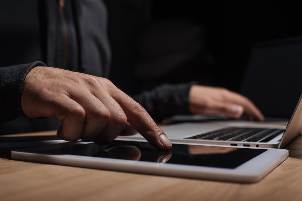 обрезанный снимок мужчины-хакера с помощью ноутбука и планшета, концепция кибербезопасности
 - Фото, изображение