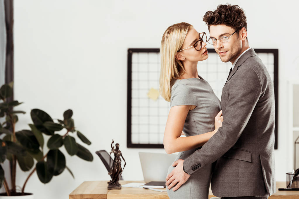 przytulanie siebie stojąc w biurze młodych prawników, biuro i flirt romans koncepcja - Zdjęcie, obraz