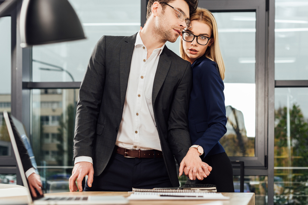 young businesspeople holding hands while flirting at workplace, office romance concept - Photo, Image