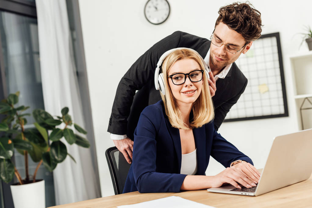 muotokuva liikemies flirttailee kollegansa kanssa kuulokkeet työpaikalla kannettava tietokone toimistossa
 - Valokuva, kuva