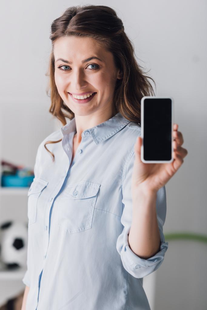 mulher adulta feliz na camisa mostrando smartphone com tela em branco na câmera
 - Foto, Imagem