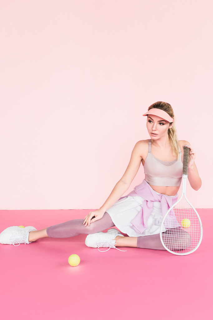 sporcumuz Tenis raket ve topları pembe üzerinde poz güneşlik şapkalı - Fotoğraf, Görsel