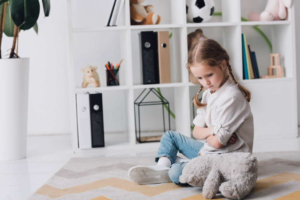 depressed little child sitting on floor with teddy bear - Photo, Image