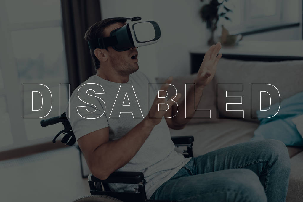 Hombre discapacitado en silla de ruedas. Hombre con gafas de realidad virtual. El hombre está gesticulando las manos. El hombre está sorprendido. Hombre morena adulto. El hombre está situado en la sala de estar. Tecnologías virtuales
. - Foto, Imagen