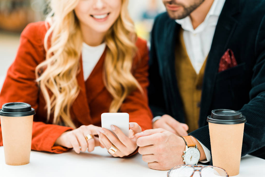 oříznutý pohled páru pomocí smartphone v kavárně s kávou jít - Fotografie, Obrázek