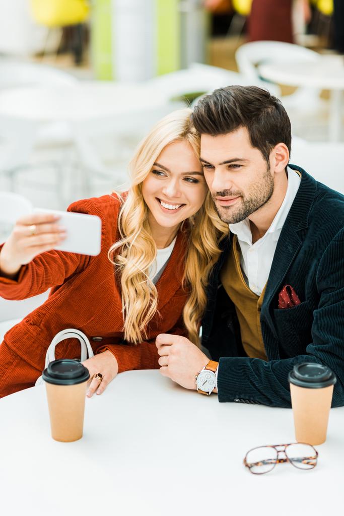 hermosa pareja con café para ir a tomar selfie en el teléfono inteligente en la cafetería
 - Foto, Imagen