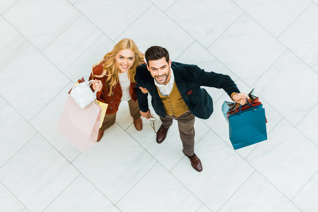 vista aérea de pareja joven sosteniendo bolsas de compras
   - Foto, imagen
