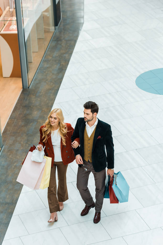 вид сверху на молодых клиентов с сумками, прогуливающимися по торговому центру
 - Фото, изображение