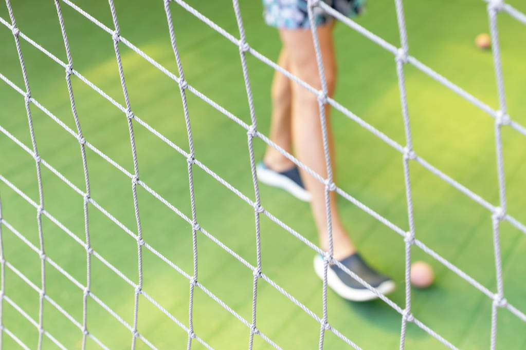 Футбольна мережа крупним планом на розмитому зеленому трав'яному футбольному полі і чоловічі ноги грають на маленькому фоні м'яча
. - Фото, зображення
