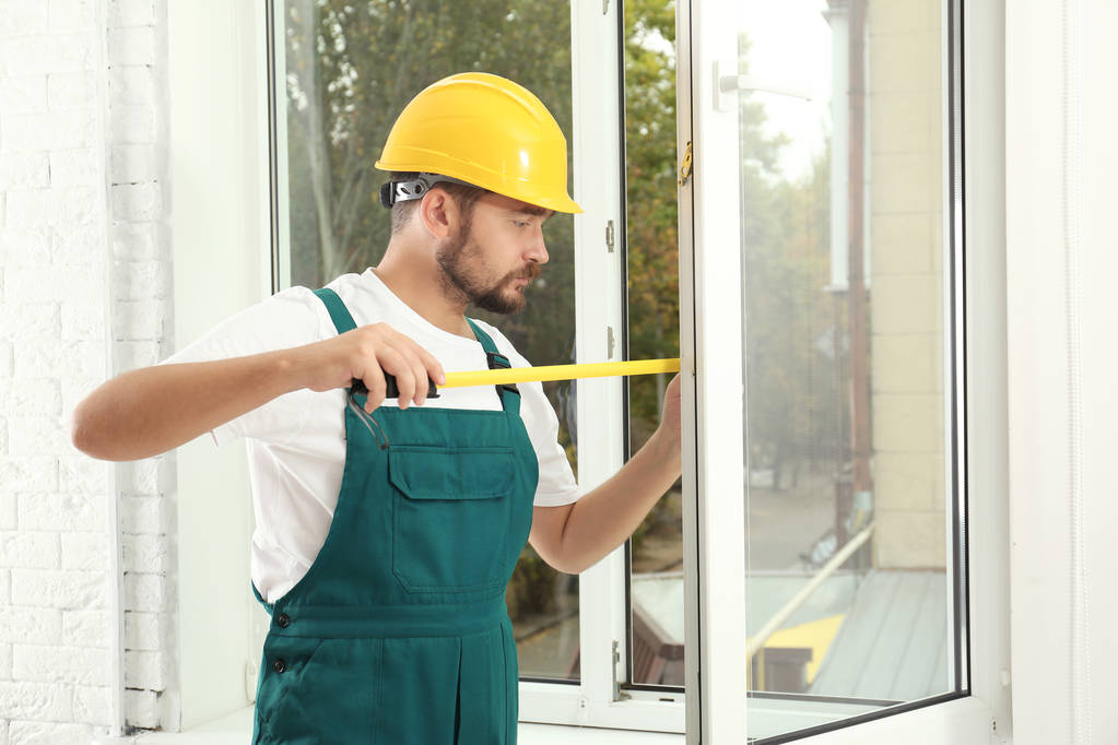 Trabalhador da construção instalando nova janela em casa
 - Foto, Imagem