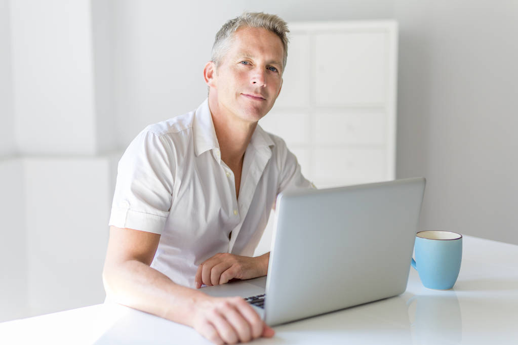 Ώριμος άνδρας που χρησιμοποιούν φορητό υπολογιστή στο γραφείο στο σπίτι - Φωτογραφία, εικόνα
