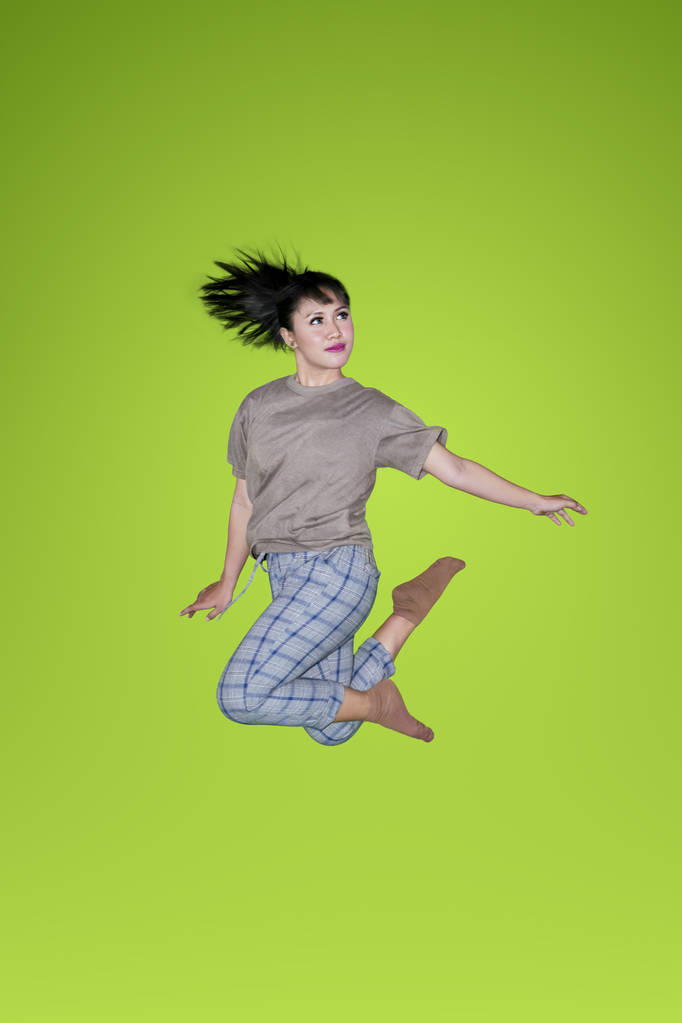 Jovem mulher asiática dançando e pulando com roupas casuais no estúdio sobre fundo tela verde
 - Foto, Imagem