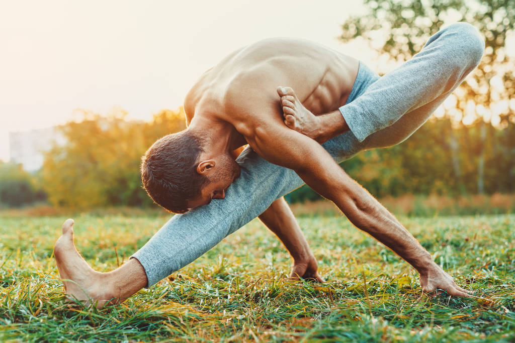 Hombre yogui entrenando en el parque de la ciudad. Luz cálida del atardecer
. - Foto, imagen