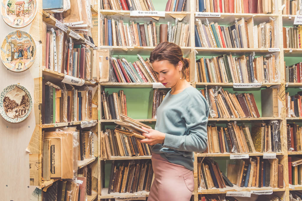 Rosja, Sankt Petersburg, 3 Listopad, 2018-dziewczyna w bibliotece ściąga książkę z półki. - Zdjęcie, obraz