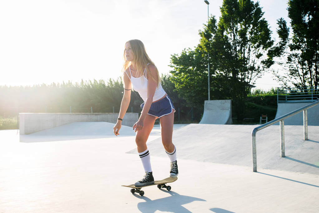Jeune femme élégante patinant en plein air - Jolie patineuse jouant avec son patin
 - Photo, image