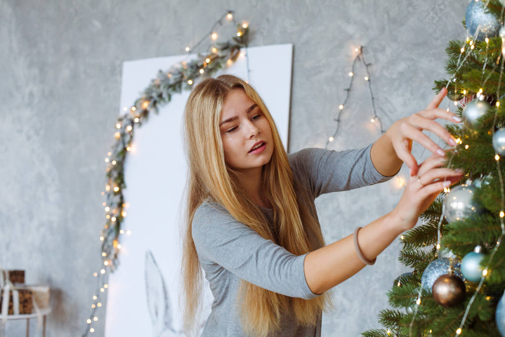 Junge Frau schmückt Weihnachtsbaum - Foto, Bild