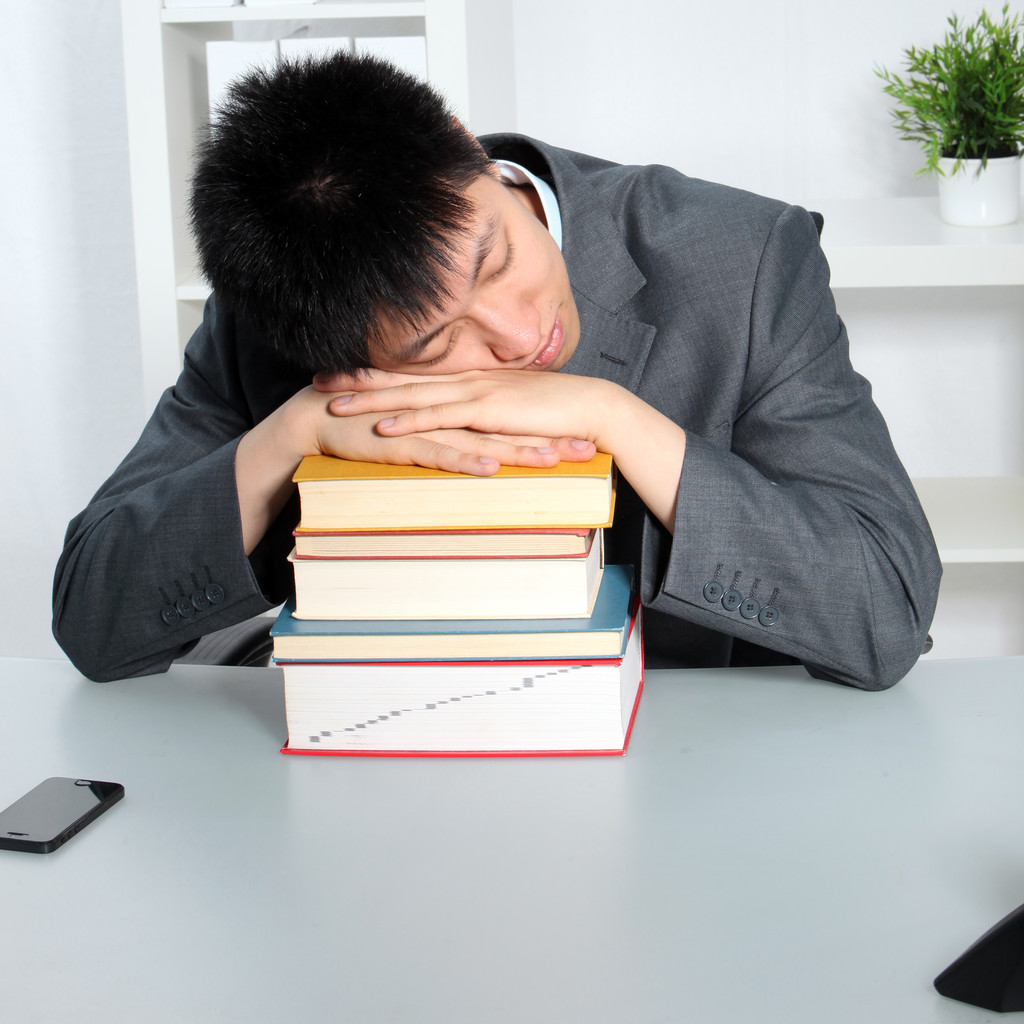 Asian man sleeping on top of a pile of books - Photo, Image