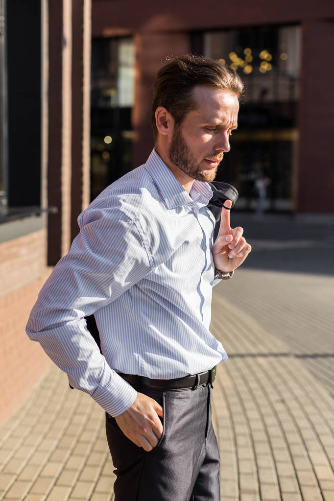 Portrait mi-long de jeune homme d'affaires avec veste dans les mains
 - Photo, image