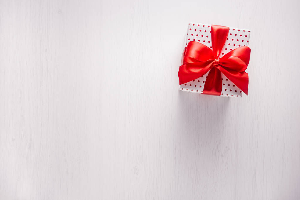 Valkoinen lahjapakkaus, jossa punaiset pilkut, nauha ja keula
 - Valokuva, kuva