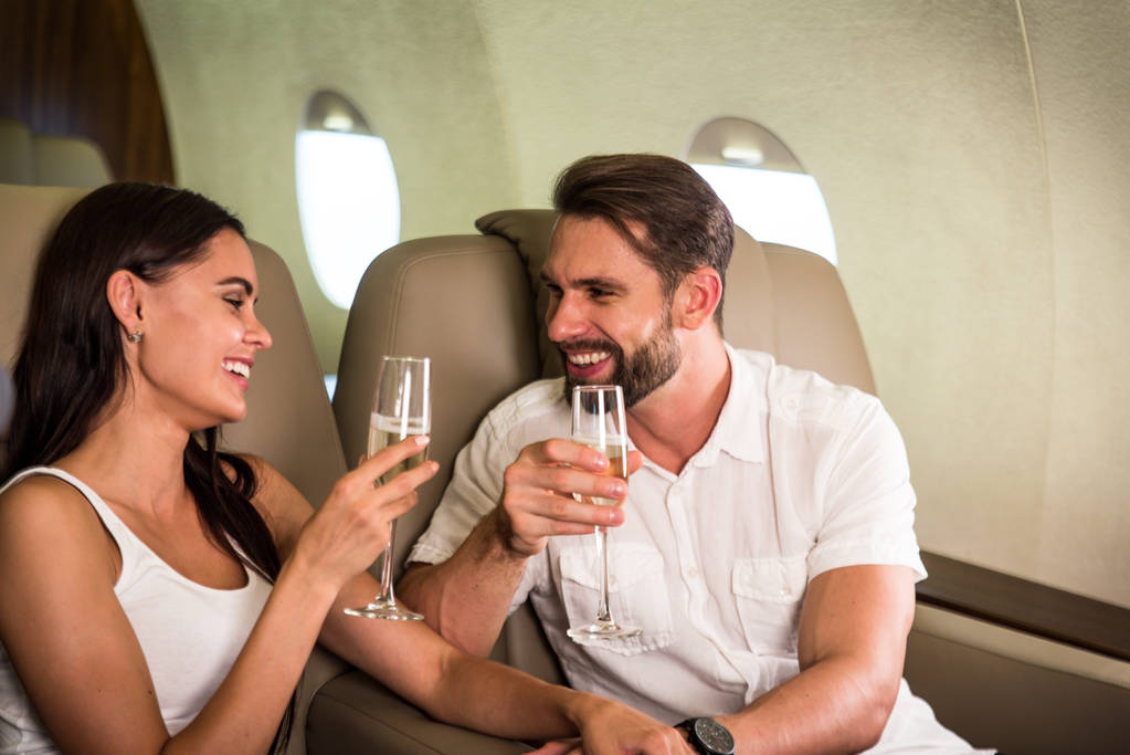 Pareja feliz viajando en un jet privado de lujo - Los adultos jóvenes viajan en un vuelo de primera clase, conceptos sobre viajes y estilo de vida
 - Foto, imagen
