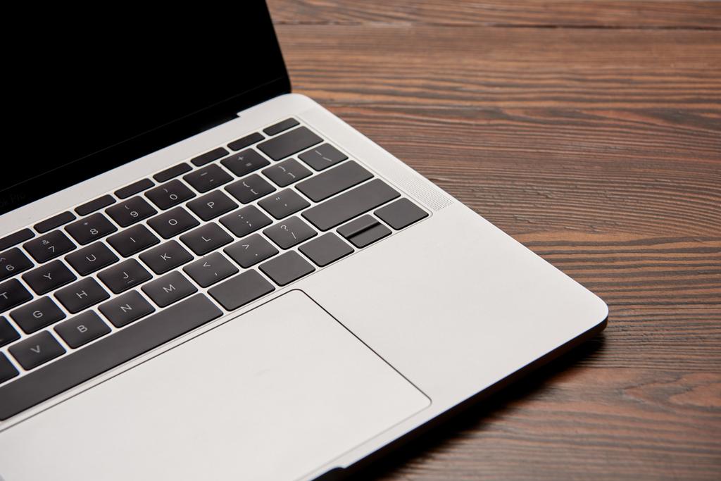 vista parziale di laptop con schermo bianco su tavolo in legno
 - Foto, immagini