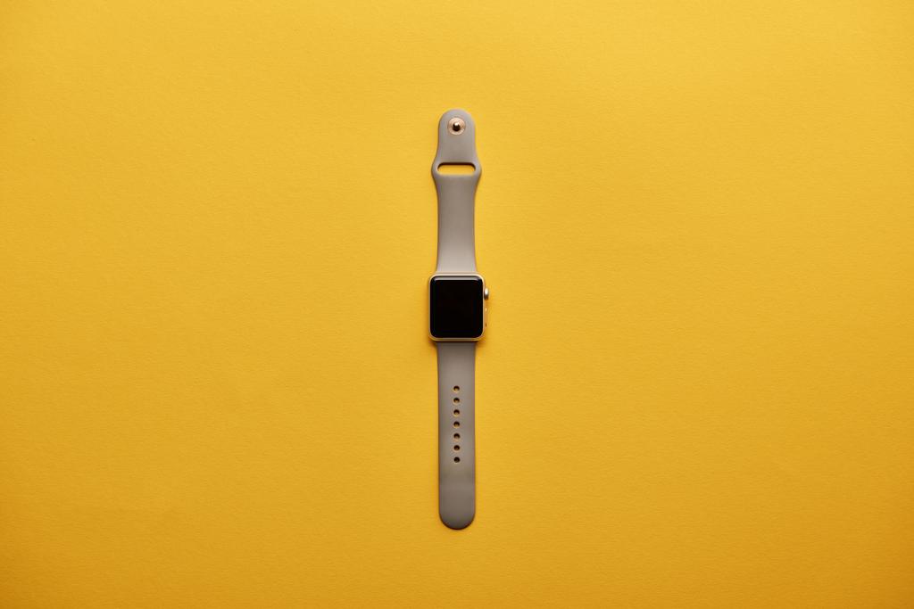 Smartwatch von oben mit leerem Bildschirm auf gelber Oberfläche - Foto, Bild
