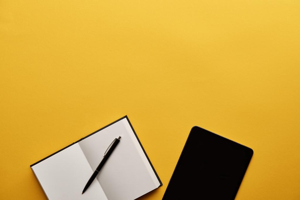 Draufsicht auf geöffnetes Notebook und Tablet auf gelber Oberfläche - Foto, Bild
