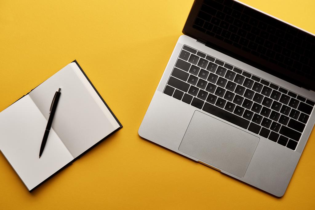 вид зверху відкритого ноутбука і ноутбука на жовтій поверхні
 - Фото, зображення