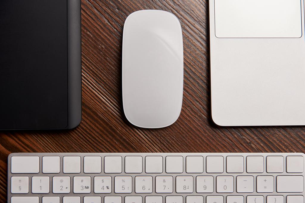 частковий вигляд ноутбука з бездротовою мишкою, графічним планшетом і клавіатурою на дерев'яному столі
 - Фото, зображення