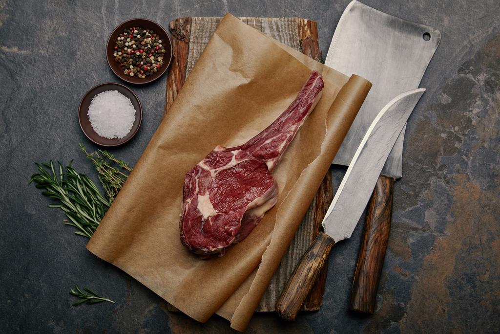 Mutfak bıçakları, baharat, ot ve gri arka plan üzerine tuz ile kagit üzerinde ham kaburga eti en iyi görünümü - Fotoğraf, Görsel