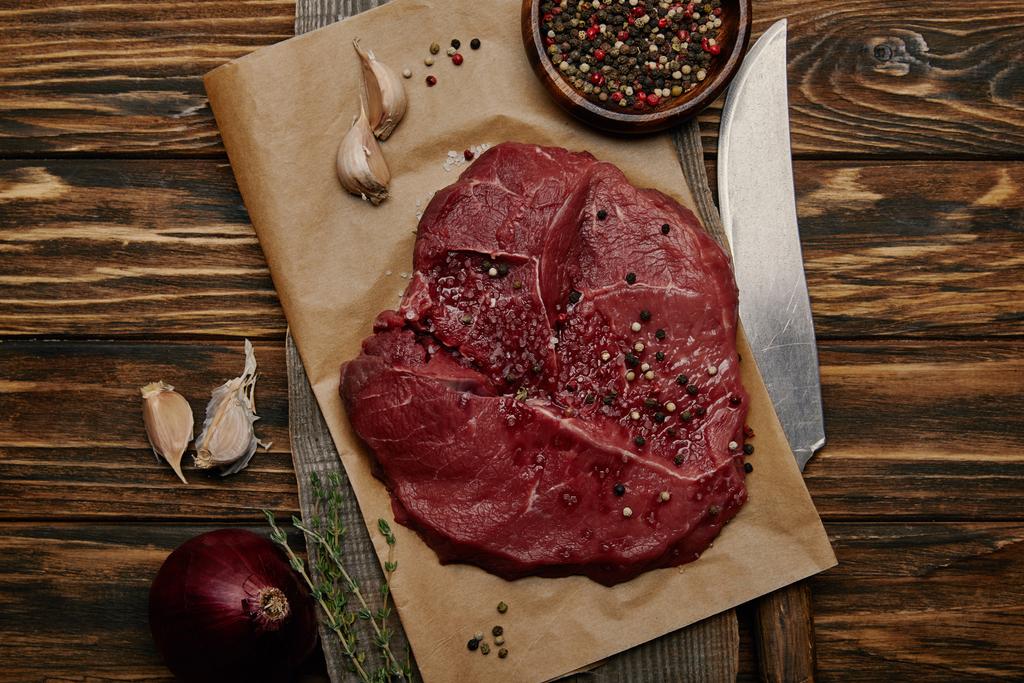 poser à plat avec de la viande fraîche crue sur du papier cuisson avec de l'ail et des épices sur fond en bois
 - Photo, image