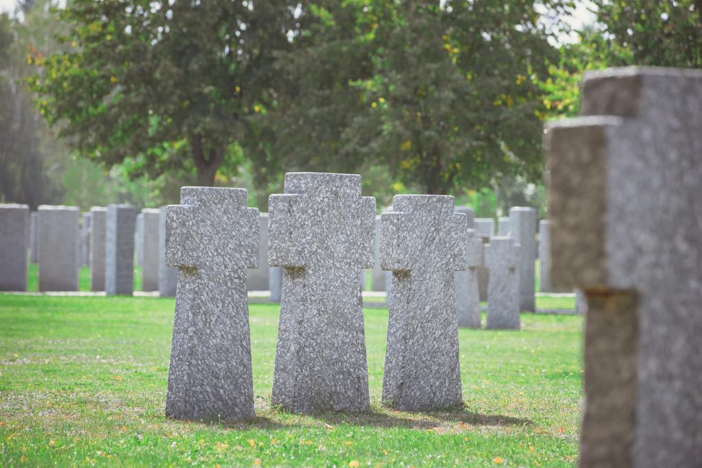 Selektivní fokus stejných starých náhrobků v řadě na trávě na hřbitově - Fotografie, Obrázek