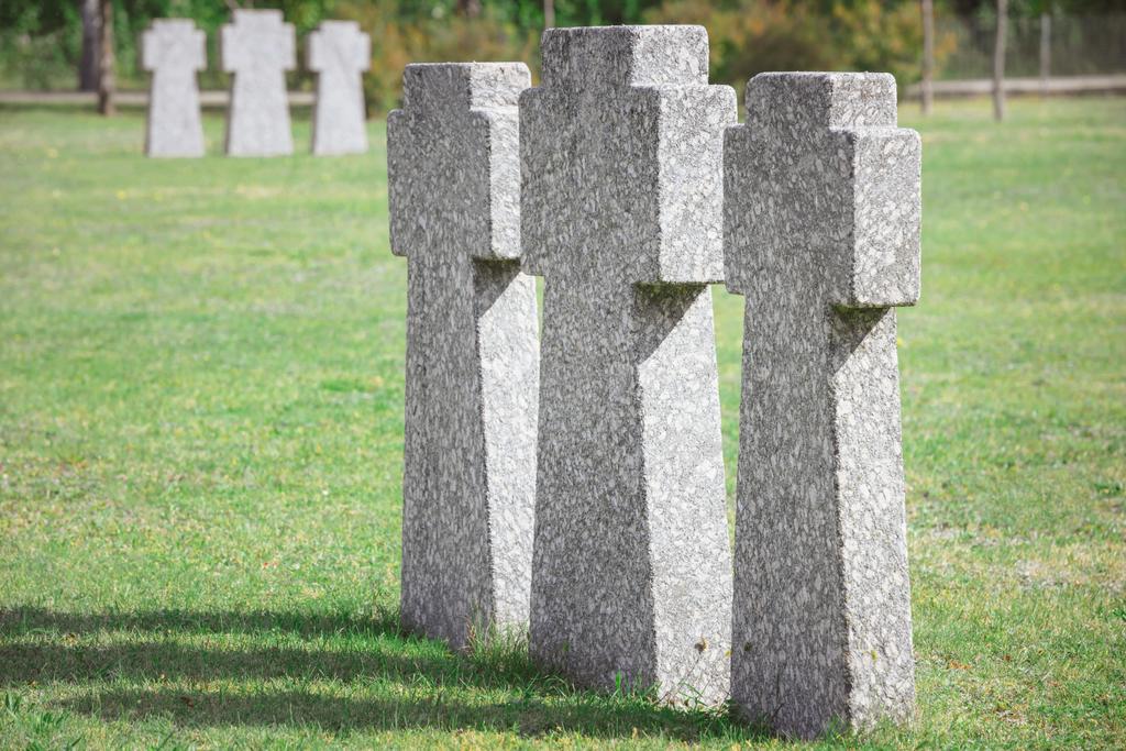 ідентичні старі меморіальні надгробки, розміщені в ряд на кладовищі
 - Фото, зображення