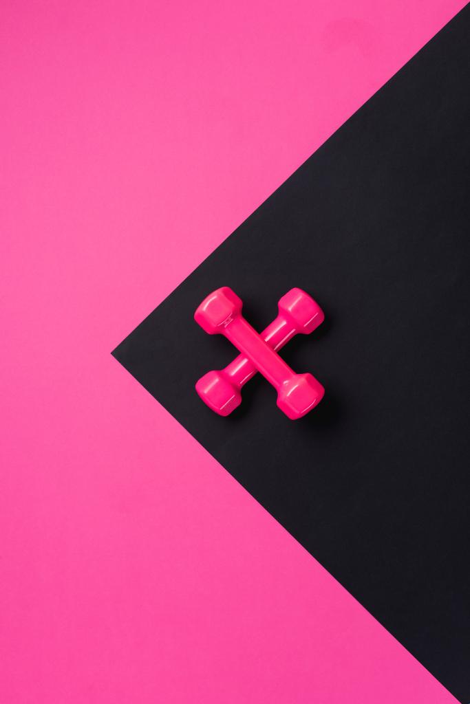 верхний вид двух скрещенных гантелей на черно-розовом фоне с копировальным пространством
 - Фото, изображение