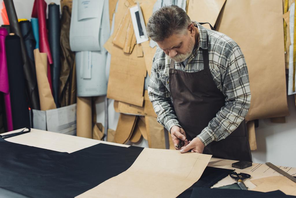 male handbag craftsman in apron working with cardboard at studio - Photo, Image