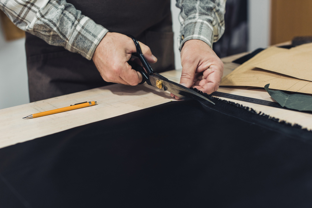 imagem cortada do artesão bolsa masculina cortando couro por tesoura na oficina
 - Foto, Imagem