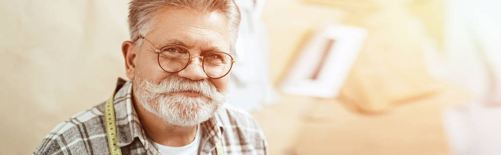 portrait de heureux artisan mature en lunettes regardant la caméra en studio
 - Photo, image