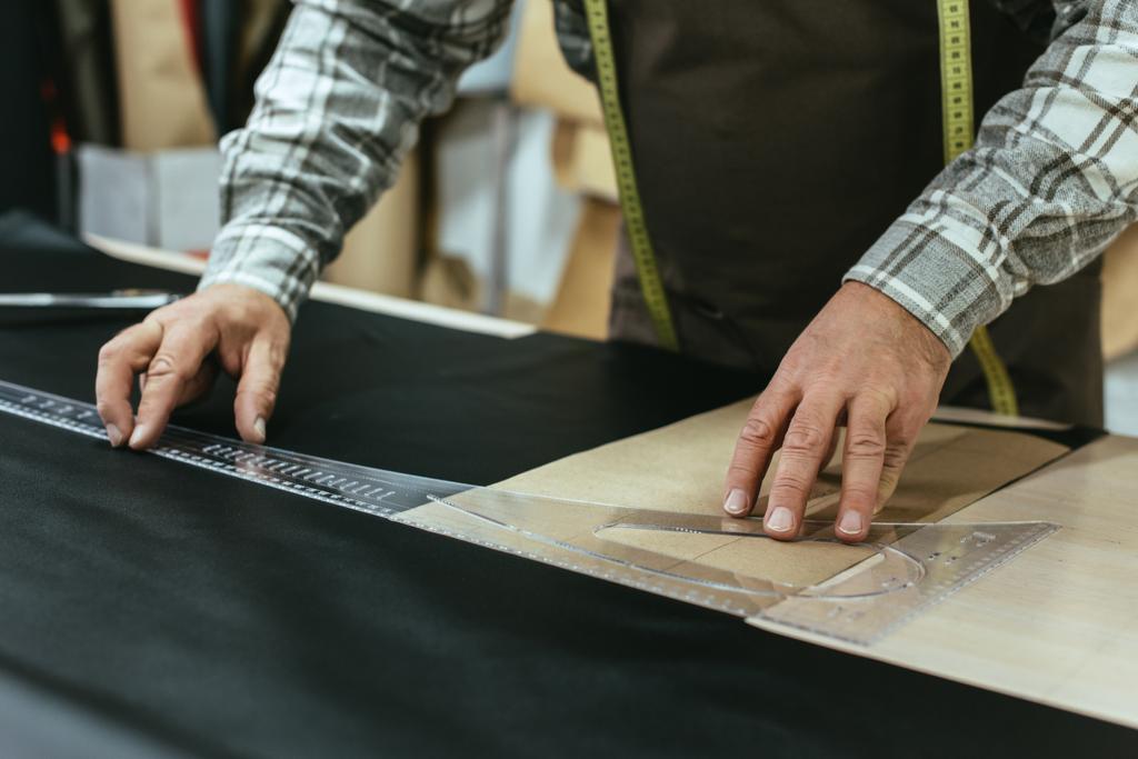 обрезанное изображение ремесленника сумочки, делающего измерения на коже в мастерской
 - Фото, изображение