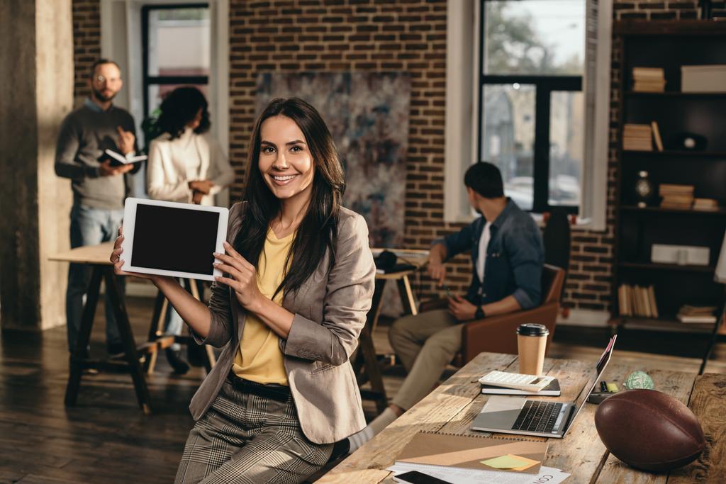 casual επιχειρηματίας εκμετάλλευση tablet με κενή οθόνη στο πατάρι γραφείο με τους συναδέλφους που εργάζονται πίσω από - Φωτογραφία, εικόνα