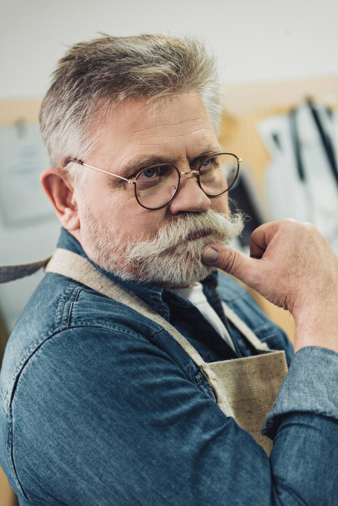 pensivo homem de meia idade artesão em avental posando na oficina
 - Foto, Imagem