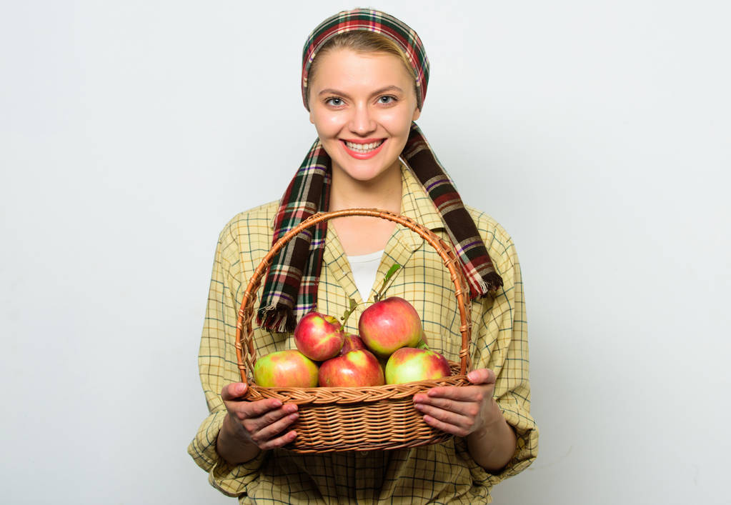 Frau fröhlich tragen Korb mit natürlichen Früchten. Gärtnerin rustikalen Stil halten Korb mit Äpfeln Ernte auf hellem Hintergrund. Bäuerin stolz auf ihre Ernte. Apfelkulturen und Gartenkonzept - Foto, Bild