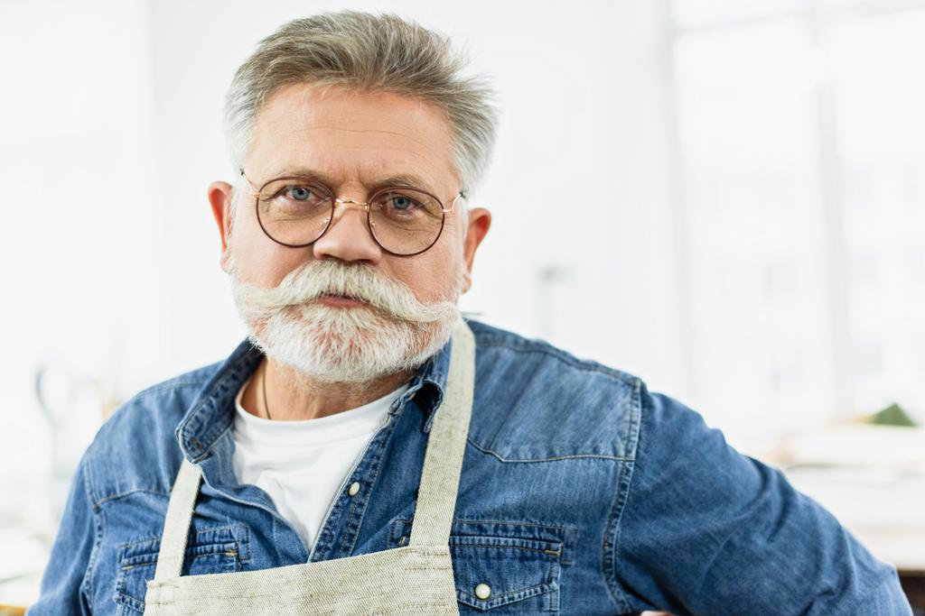 retrato de artesano de mediana edad en delantal posando en el taller
 - Foto, imagen